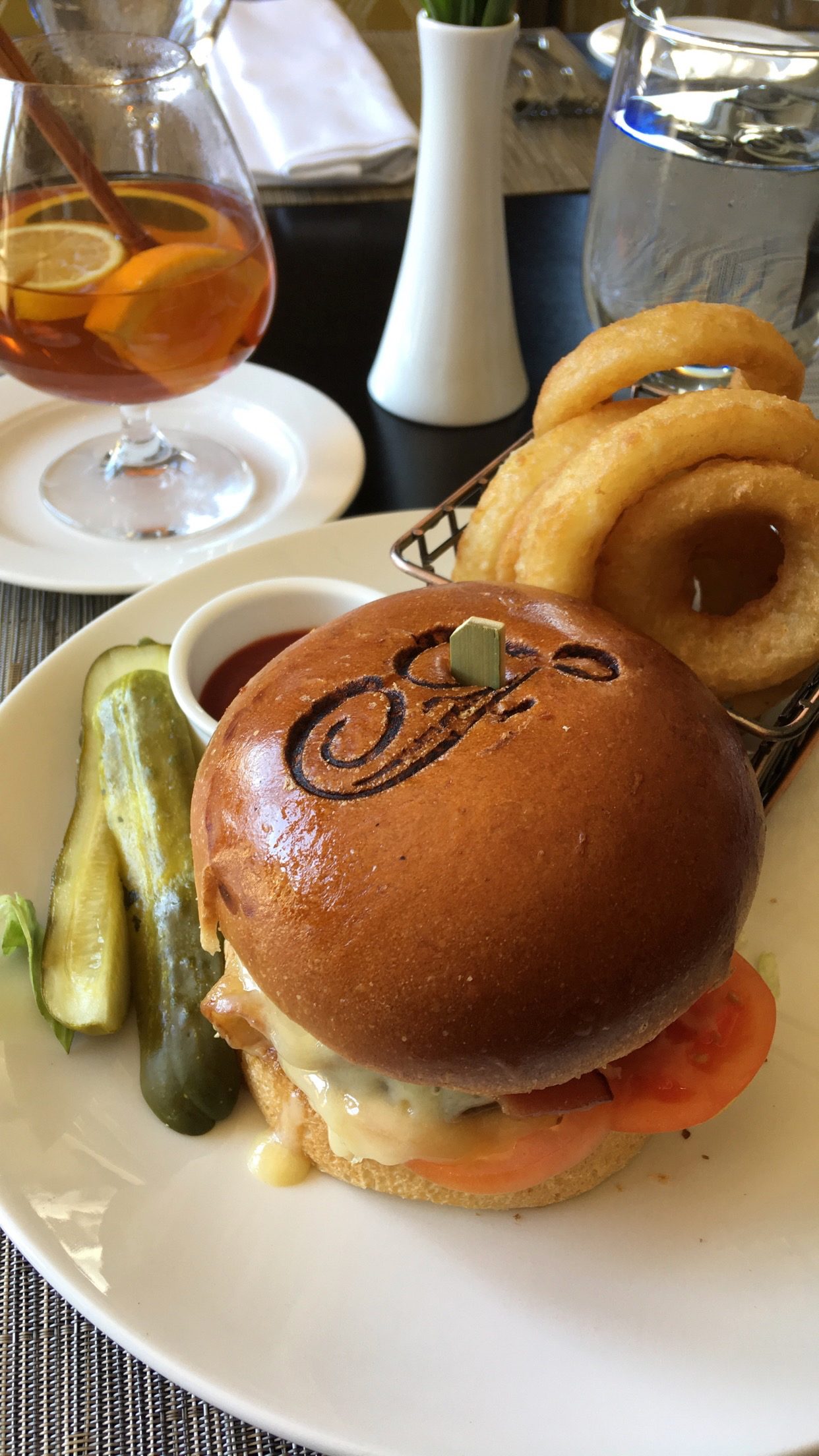 Branded cheeseburger with onion rings at table
