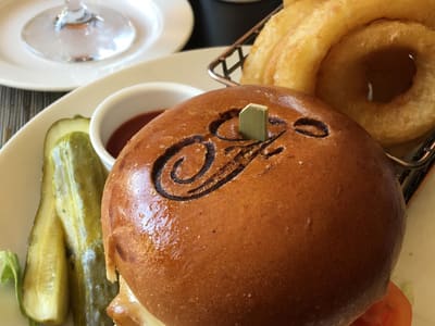Branded cheeseburger with onion rings at table