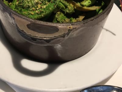 Sautéed fiddleheads in rustic restaurant pot